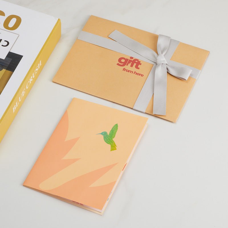 3D Pop-Up Greeting Card with a closed cover featuring a green hummingbird, alongside gift packaging