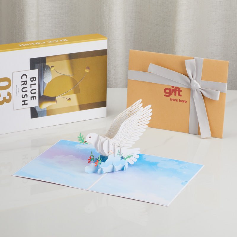White dove pop-up card with peaceful sky background displayed with gift packaging