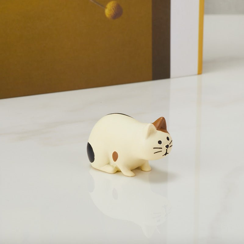 Cute crouching cat figurine on a table, side view