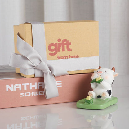 Gift box with silver ribbon and cow phone holder with corn snack