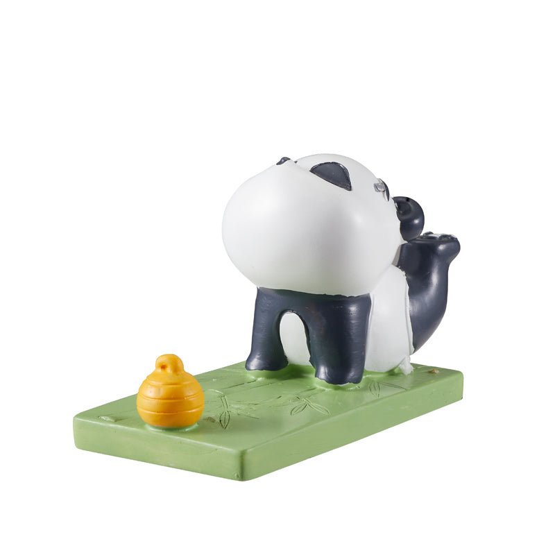 panda figurine phone holder on a green base with a yellow beehive