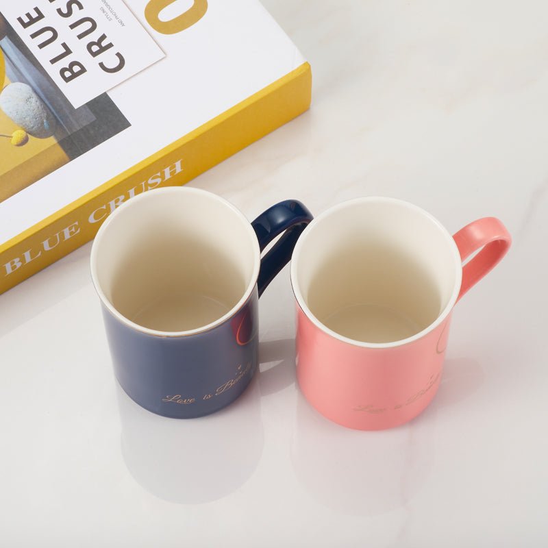 Top view of Love is Beauty ceramic mugs in blue and pink