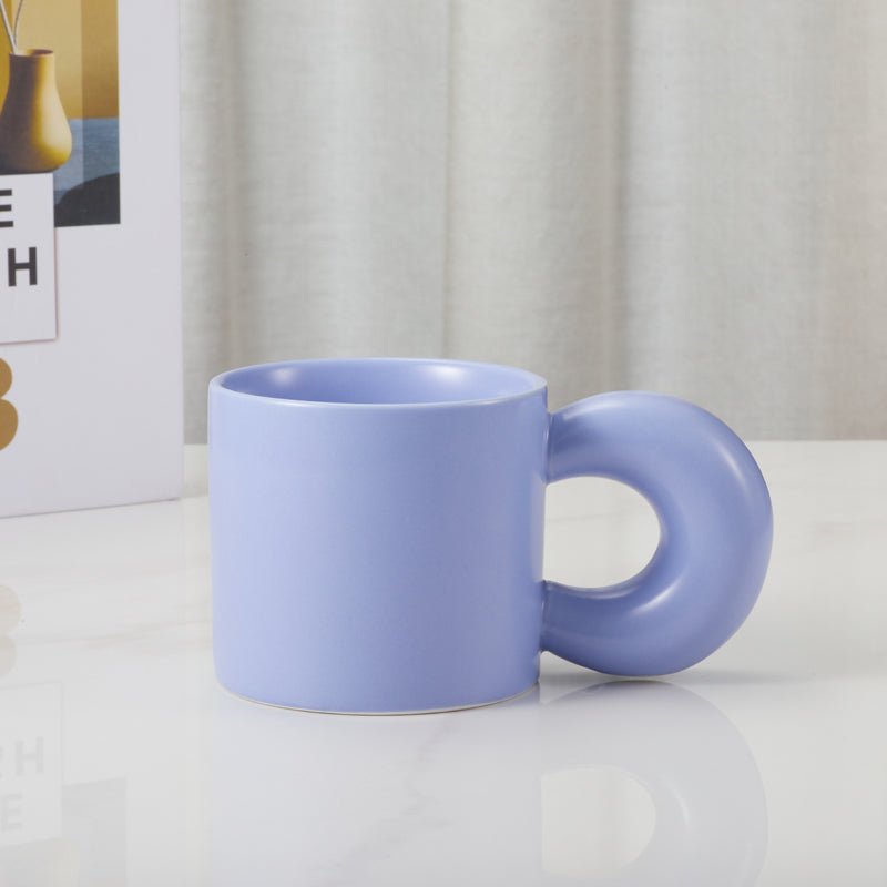 Light blue ceramic mug with a round handle displayed on a table