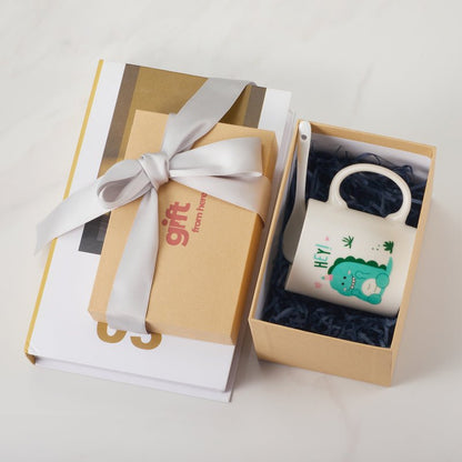 Gift box with white ceramic mug with dinosaur illustration inside