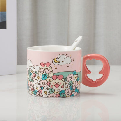 Ceramic mug with a pink floral design and a coral-colored floral shaped handle, placed on a table