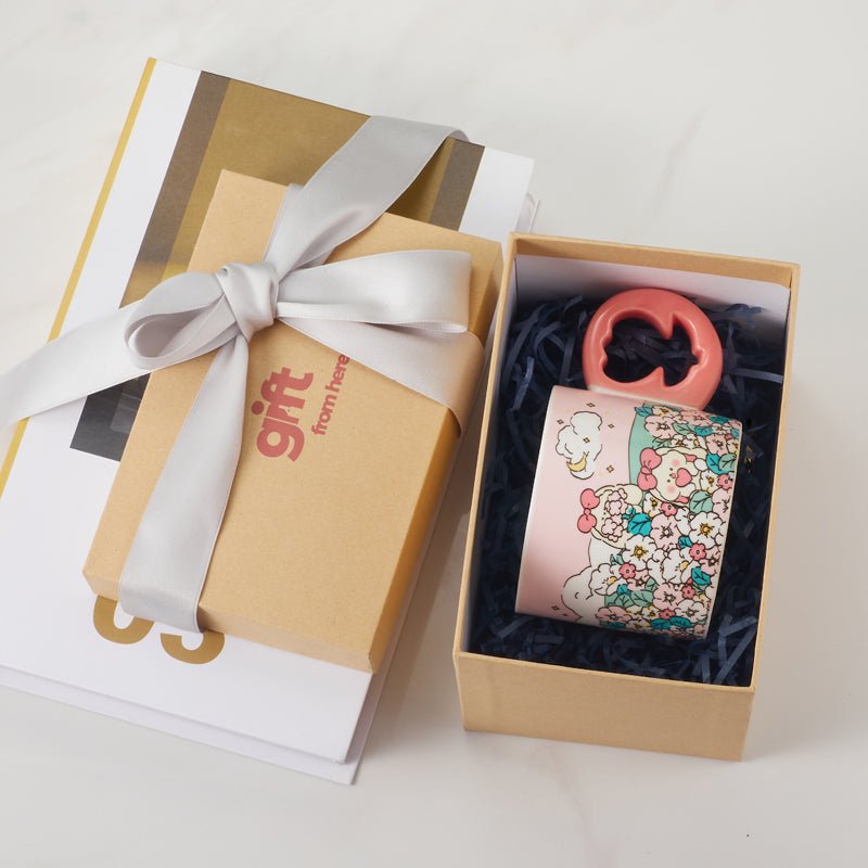 Ceramic mug with a pink floral design and a coral-colored floral-shaped handle, in a gift box