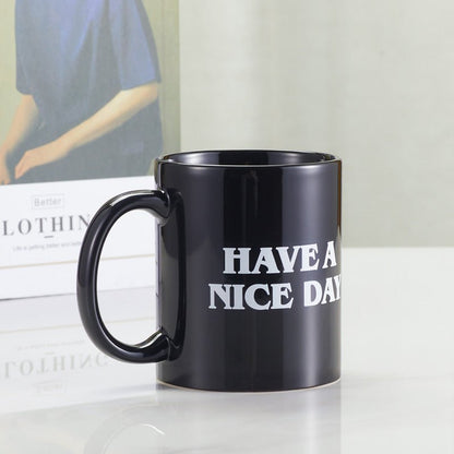 Side view of black "Have A Nice Day" coffee mug with book in the background