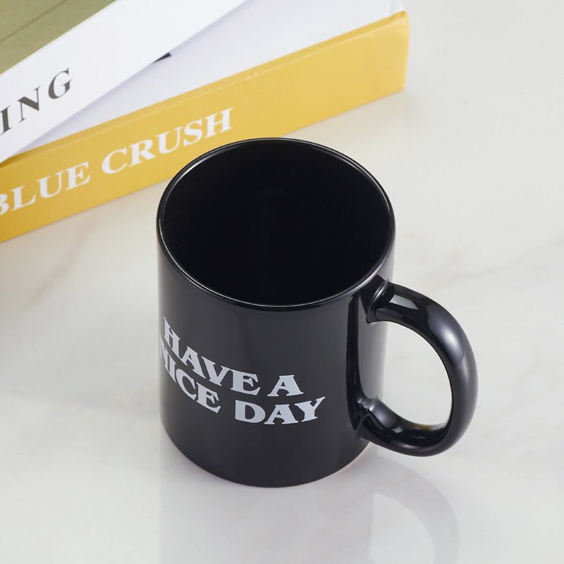 Top view of black "Have A Nice Day" coffee mug on a white table