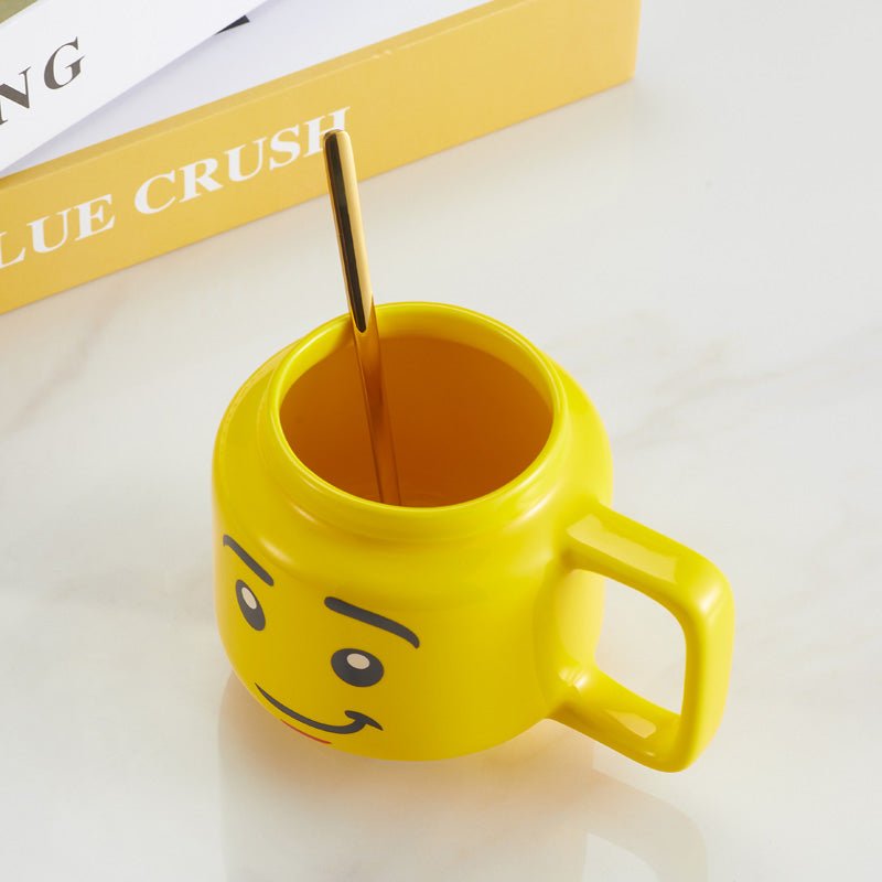 Open yellow mug with a smiling face design and a golden spoon placed inside